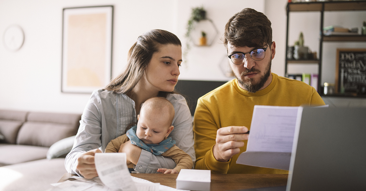 A couple with bills looks at a laptop.